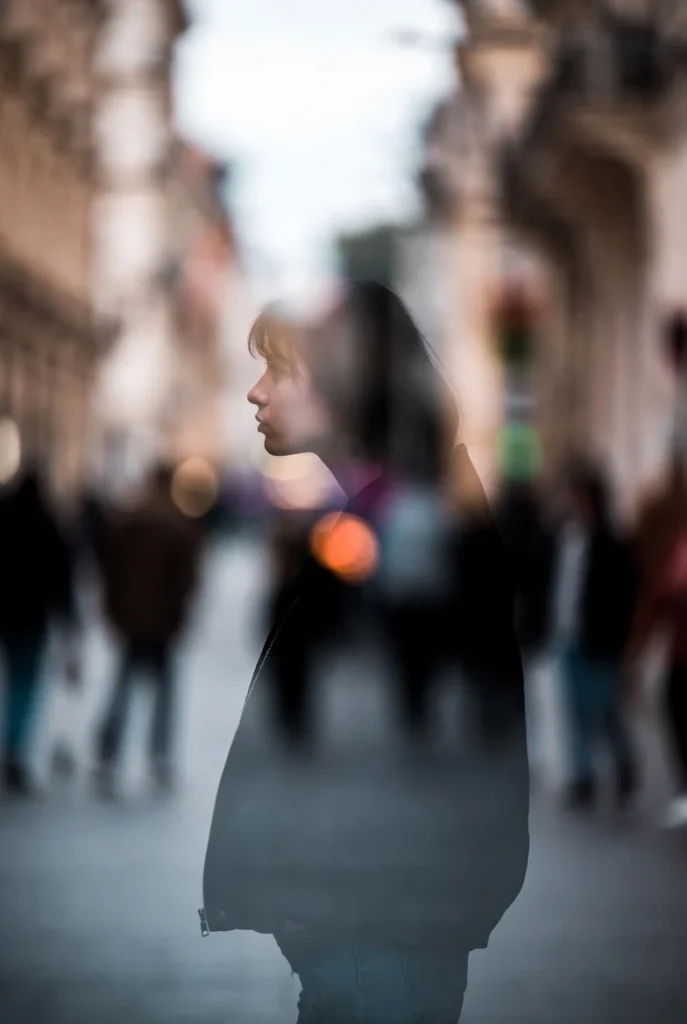 The Mattering Effect | What Is The Mattering Effect? Why Feeling Seen, Valued, and Needed Changes Everything Blurred city scene showing a solitary woman partially fading into the background, symbolizing The Great Erasure and the modern experience of feeling unseen, emotionally disconnected, and invisible in plain sight.